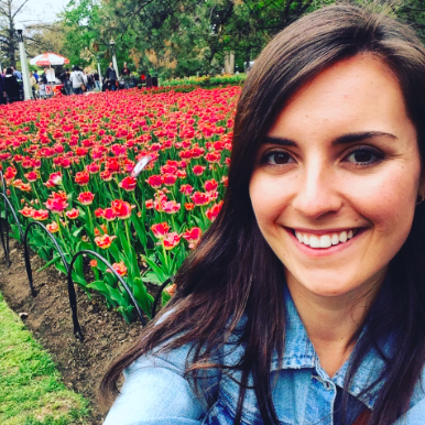 Maude looking at the camera with a field of red flowers behind her.