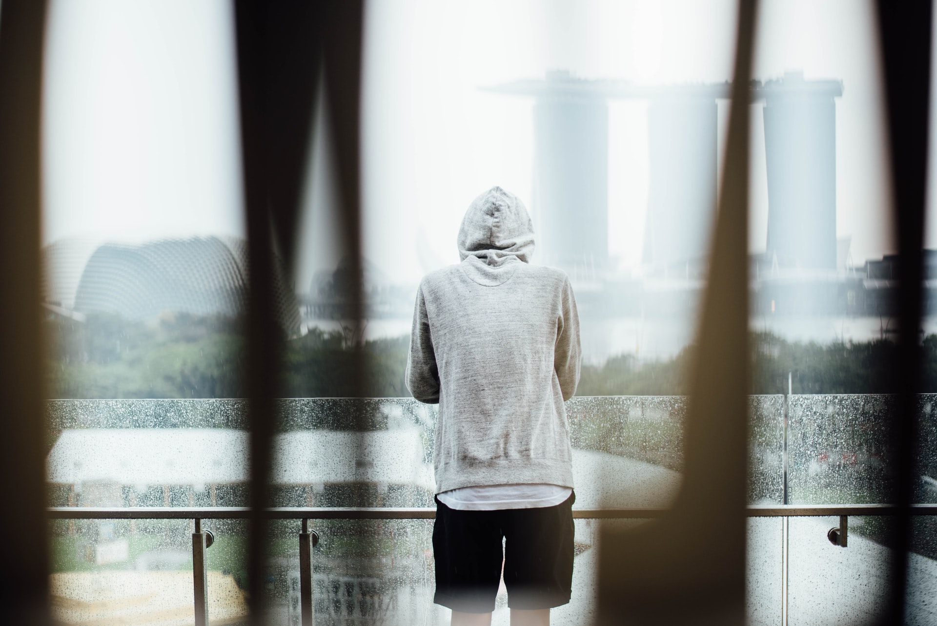 Person in hoodie back-on looking at water alone.